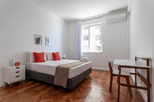 1 dormitorio con cama con almohadas rojas y escritorio en Maravilha em Copacabana - 3 Quartos - ML301, en Río de Janeiro
