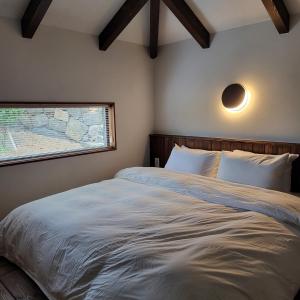 a bedroom with a large bed with a window at Juwoldam in Jeju