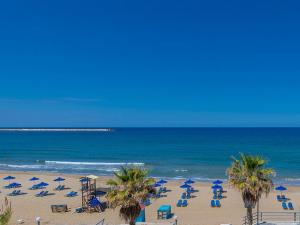 una playa con sillas y sombrillas y el océano en Ruby 'n Emerald studio's en Rethymno