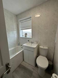 a bathroom with a toilet and a sink and a tub at MMC Serviced accommodation in Leigh