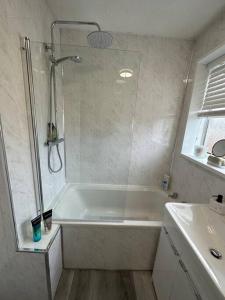 a bathroom with a shower and a tub and a sink at MMC Serviced accommodation in Leigh