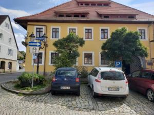 zwei Autos, die vor einem gelben Gebäude geparkt sind in der Unterkunft Alte Poststation Goldener Hirsch in Emskirchen
