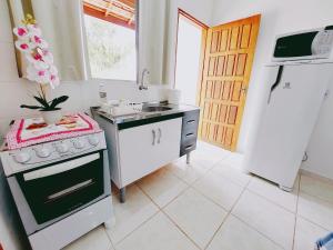 La cuisine est équipée d'une cuisinière, d'un évier et d'un réfrigérateur. dans l'établissement Recanto Bela Vista, à Peruíbe