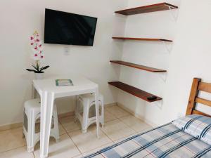 1 dormitorio con mesa y TV en la pared en Recanto Bela Vista en Peruíbe