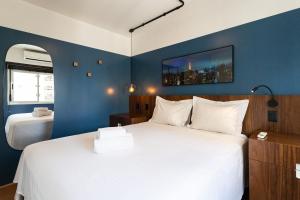a bedroom with a white bed and a blue wall at Apto com máquina de lavar perto do metrô Trianon in Sao Paulo +25 photos