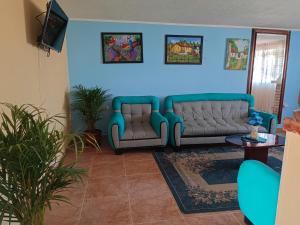 una sala de estar con 2 sofás y una pared azul en Alojamiento Chalet - Monguí, en Monguí