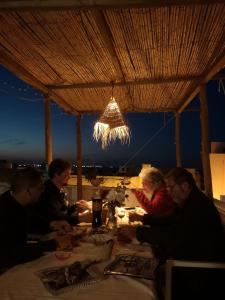 un grupo de personas sentadas en una mesa por la noche en Dar Evelyne en Mahdia