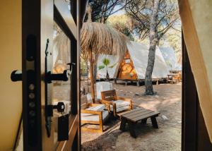 drzwi otwarte do namiotu z krzesłami i ławką w obiekcie TAIGA Conil w mieście Conil de la Frontera