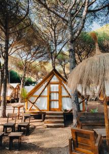a cabin with benches and a straw hut at TAIGA Conil in Conil de la Frontera