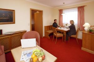 dos personas sentadas en una mesa en una habitación de hotel en Appartementhaus Absmeier, en Bad Füssing