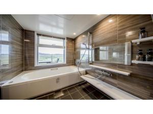 uma casa de banho com uma banheira e uma janela em Lieta Nakayama - Vacation STAY 22439v em Nago