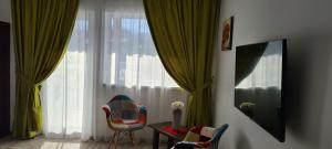 Cette chambre comprend une chaise, une table et une grande fenêtre. dans l'établissement Cabana Floare de Colt 2, à Râșnov