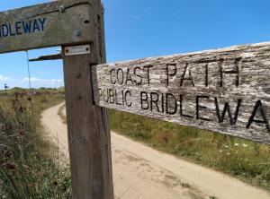 a wooden sign for a coast path and bike buildeway at The Gallery Lodges in Braunton