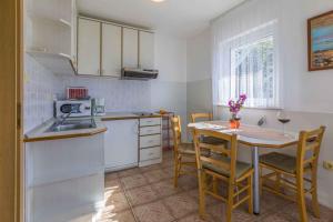 One-Bedroom Apartment in Crikvenica I في دْرامالج: مطبخ مع طاولة وكراسي ومطبخ مع أجهزة بيضاء