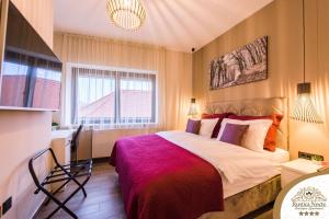 a bedroom with a large bed with a red blanket at Rustica Nocte Boutique Apartments in Požega