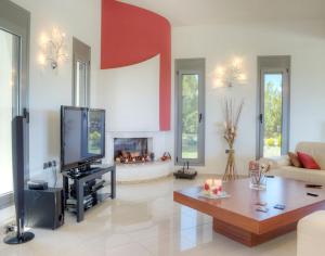 a living room with a tv and a fireplace at Villa Artemis in Koskinou