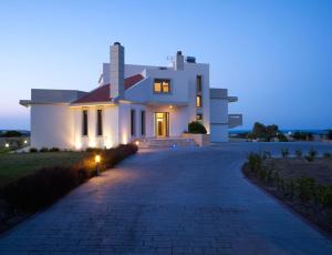 uma grande casa branca à noite com uma entrada em Villa Artemis em Koskinou