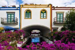 a building with a waterway in front of it with purple flowers at Sunshine 435 in Playa del Ingles