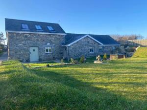 a stone house with a lawn in front of it at Bwthyn Gwenyn Yr Haf Summer Bee Barns in Nefyn