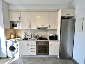 kuchnia z białymi szafkami i lodówką ze stali nierdzewnej w obiekcie Loft moderno en buena ubicación w mieście Terrassa