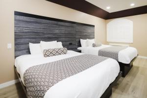 two beds in a hotel room with white at Sapphire Inn & Suites in Channelview