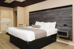 Schlafzimmer mit einem großen Bett mit einem Kopfteil aus Holz in der Unterkunft Sapphire Inn & Suites in Channelview