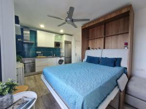 a bedroom with a blue bed and a kitchen at Acogedor estudio en Candelaria en primera línea de mar in Candelaria