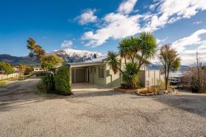 a house with palm trees and a mountain in the background at Lakeview in Lake Hawea
