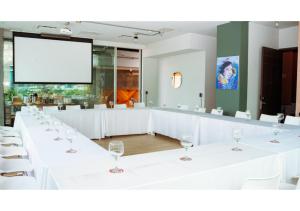 a conference room with white tables and chairs and a screen at Selina Parque 93 Bogota in Bogotá