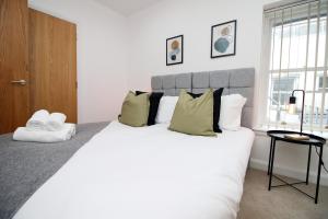 ein Schlafzimmer mit einem großen weißen Bett mit grünen Kissen in der Unterkunft No2 Under the Clock by SSW - Cardiff City Centre in Cardiff