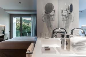 baño con lavabo, cama y espejo en Hotel Sorli Emocions, en Vilassar de Dalt