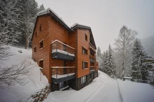 a large brick building in the snow with snow at Vlčí Stopa Apartments in Pec pod Sněžkou
