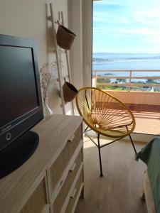 salon z telewizorem, krzesłem i oknem w obiekcie San Vicente Views w mieście San Vicente do Mar