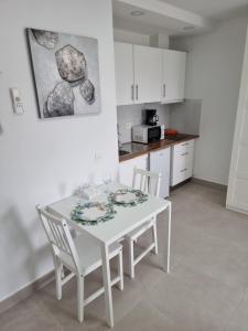 a white kitchen with a white table and chairs at APARTAMENTOS ELEMAR free luggage storage in Málaga