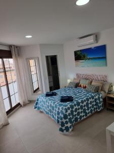 a bedroom with a bed with a blue and white blanket at APARTAMENTOS ELEMAR free luggage storage in Málaga