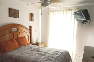 um quarto com uma cama, uma ventoinha de tecto e uma televisão em Departamento amplio y amueblado en Marina Diamante em Acapulco