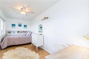 een slaapkamer met een bed en een plafondventilator bij Paradise Breeze Retreat- Absolute Oceanfront with Hot Tub! in Keaau
