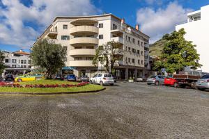 a parking lot with cars parked in front of a building at Machico City Apt in Machico