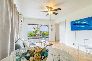 een woonkamer met een bank en een plafondventilator bij Paradise Breeze Retreat- Absolute Oceanfront with Hot Tub! in Keaau