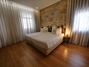 een slaapkamer met een groot wit bed met witte kussens bij Porta Nobre - Exclusive Living Hotel in Porto