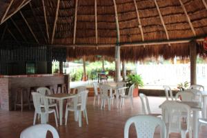 een restaurant met witte stoelen en tafels en een bar bij CABAÑAS CAMPESTRES LA AURORA DEL LLANO in Villavicencio