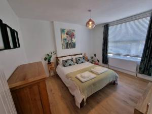 um quarto com uma cama e uma grande janela em Cheerful 3 bedroom home with garden! em Torquay