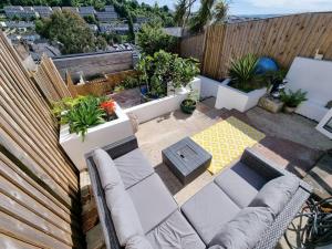 a patio with a couch and some plants and a fence at Cheerful 3 bedroom home with garden! in Torquay