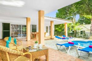 a patio with wicker chairs and a swimming pool at Villa Agua Marina in Binibeca