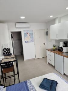 a kitchen with white cabinets and a table and chairs at APARTAMENTOS ELEMAR free luggage storage in Málaga