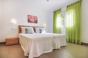 1 dormitorio con 1 cama grande y cortinas verdes en Villa Verano en Cala Galdana