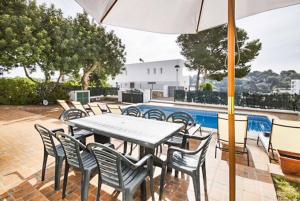 un patio con mesa, sillas y piscina en Villa Verano, en Cala Galdana