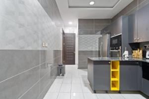 una cucina con elettrodomestici in acciaio inossidabile e pareti grigie di Sophisticated 4-Bedroom Condo in VI a Igboshere