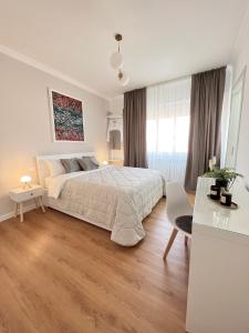 a white bedroom with a large bed and a table at Corso Venezia in Mestre