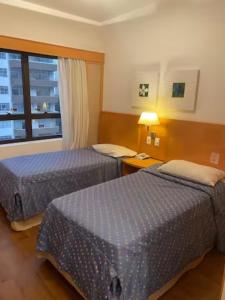 Cette chambre comprend 2 lits et une fenêtre. dans l'établissement Flat com sacada e piscina, à São Paulo